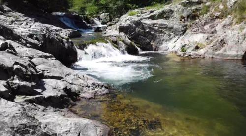 une rivière avec une cascade sur le flanc d'une montagne dans l'établissement Maison typique ardéchoise et sa rivière privée, à La Celle-sous-Gouzon