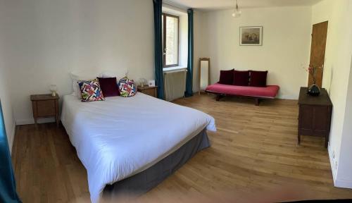 une chambre avec un grand lit et une chaise rouge dans l'établissement Maison typique ardéchoise et sa rivière privée, à La Celle-sous-Gouzon