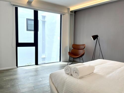 a bedroom with a bed and a chair and a window at Lesplanade By Wynwood House in Panama City
