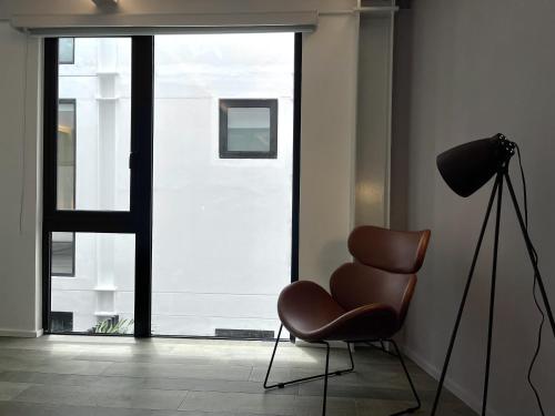 a brown chair in a room with a large window at Lesplanade By Wynwood House in Panama City