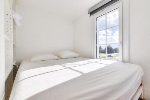 un lit blanc dans une chambre blanche avec une fenêtre dans l'établissement Résidence Port Bourgenay - maeva Home - Appartement 3 pièces 5 personnes - Sélection MAE-5371, à Talmont-Saint-Hilaire
