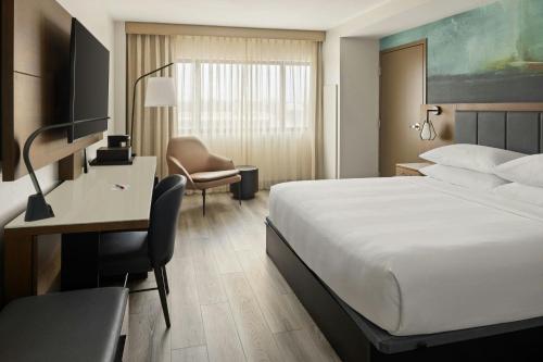 a hotel room with a bed and a desk and a chair at Oshkosh Marriott Waterfront Hotel & Convention Center in Oshkosh