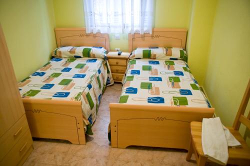 two beds in a small room with two bedsitures at Pensión Aries II in Cuenca