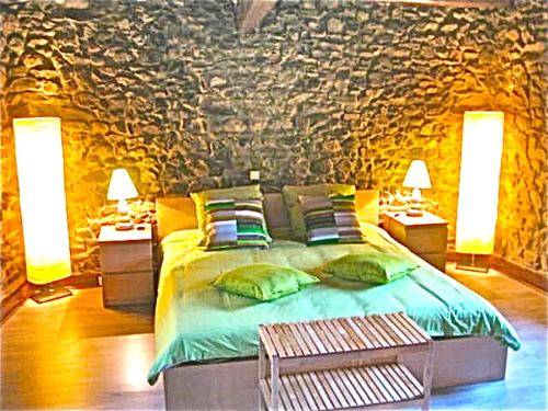 a bedroom with a bed with two lamps and a stone wall at Le Relais in Lavoûte-Chilhac