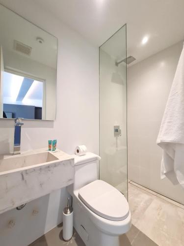 a white bathroom with a toilet and a sink at Lesplanade By Wynwood House in Panama City