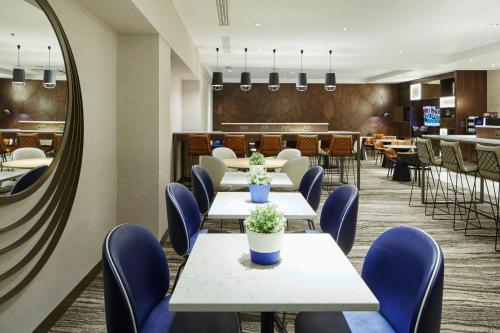 a dining room with tables and chairs and a mirror at London Marriott Hotel Regents Park in London