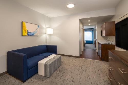 a living room with a blue couch and a kitchen at Holiday Inn Express & Suites Aiken by IHG in Aiken