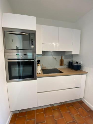 une cuisine avec des armoires blanches et un micro-ondes dans l'établissement Le Lagon Bleu, à Fréjus