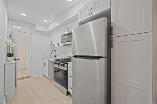 a kitchen with white cabinets and a refrigerator at The Cozy District Den Stay in Washington