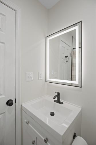 a white bathroom with a sink and a mirror at The Cozy District Den Stay in Washington