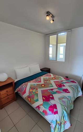 a bedroom with a bed with a colorful comforter at Algarrobo Depto Vista Mar 3D2B, Pinares Canelillo in Algarrobo
