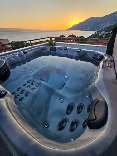 a jacuzzi tub with the sunset in the background at Apartman Štorija in Brela