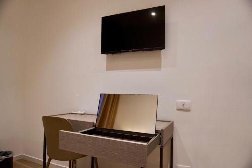 a laptop sitting on a table with a tv on a wall at Palazzo Simposio in Torremaggiore