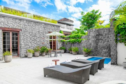 a patio with tables and chairs next to a stone wall at JW Marriott Guanacaste Resort & Spa in Tamarindo