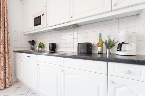a kitchen with white cabinets and a black counter top at Seepferdchen Freetied in Sierksdorf