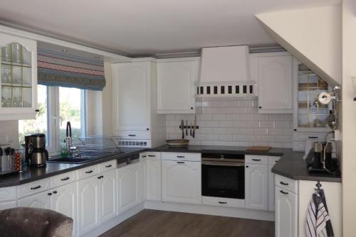 eine Küche mit weißen Schränken und schwarzen Arbeitsplatten in der Unterkunft Sonnenschein 9184 - Neujellingsdorf in Neujellingsdorf