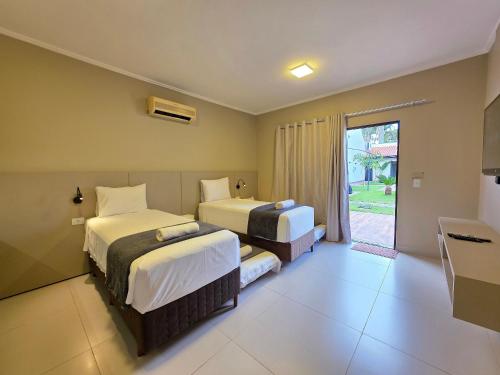 a hotel room with two beds and a window at 2 Suítes Novas Alto padrão Área de Lazer Ampla in Foz do Iguaçu