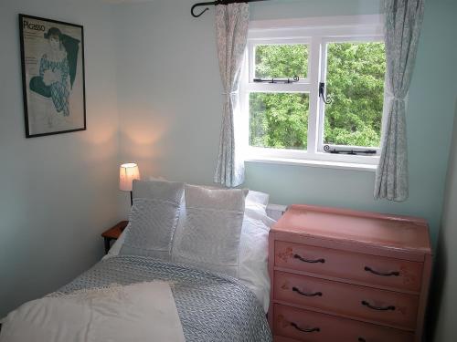 une chambre avec un lit et une commode avec une fenêtre dans l'établissement Gun Hill Cottage, à Horam
