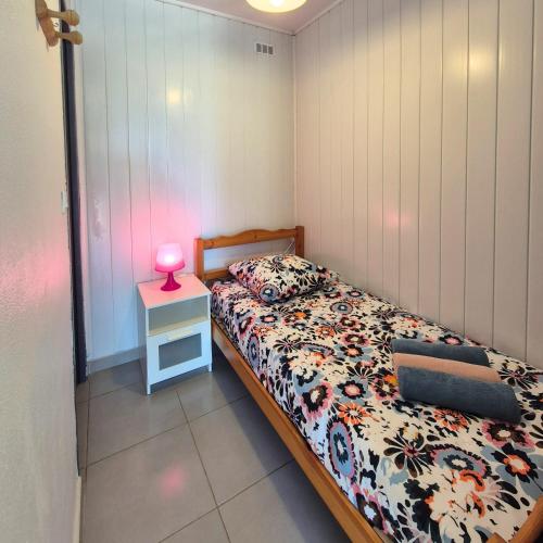 - une chambre avec un lit et une lampe rose sur une table dans l'établissement L'ECUME - Logement les pieds dans le sable, à Mauguio