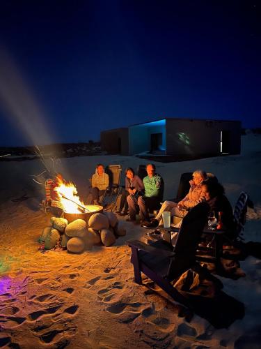 a group of people sitting around a fire on the beach at Dpto frente a la playa Beach Front Bahia turquesa in La Ventana