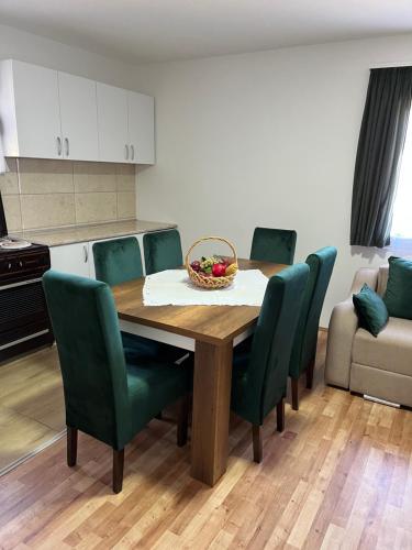 a dining room table with green chairs and a bowl of fruit at Vikendica Bellini 3 in Soko Banja
