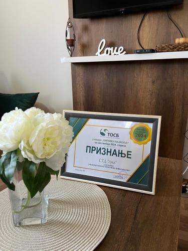a vase with white flowers and a sign on a table at Vikendica Bellini 3 in Soko Banja
