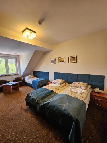 a hotel room with two beds and a couch at Pensjonat Leśny Dworek SPA & Garden Uzdrowisko wśród Natury in Cisów