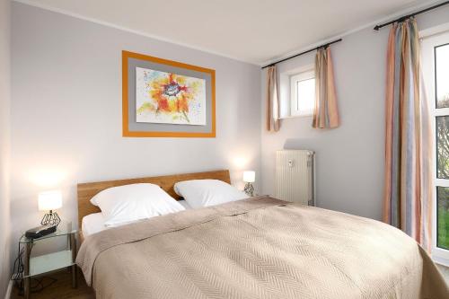 Un dormitorio con una cama grande y dos ventanas. en Am Golfplatz 25 Wohnung 4, en Stakendorfer Strand