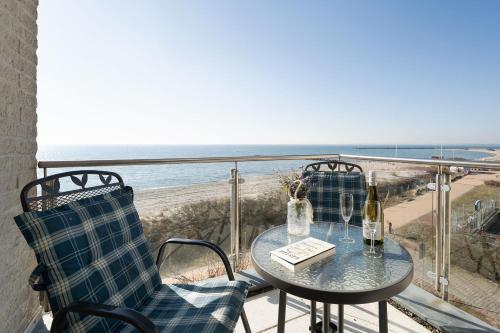 a table and chairs on a balcony with a view of the beach at Am Südstrand 9 Strandburg II in Fehmarn