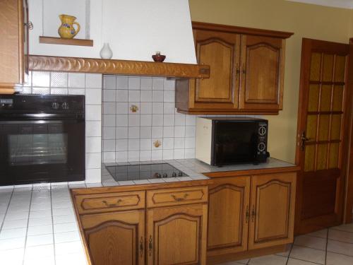 une cuisine avec des armoires en bois et un micro-ondes noir dans l'établissement Gîte les chateaux, à Châtenois