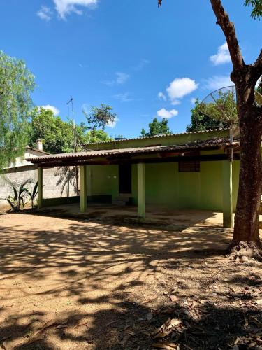 a green building with a tree in front of it at Casa Jatobá in Abadiânia