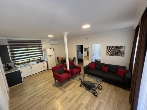 a living room with a couch and two red chairs at Keyif Pension & Aparts in Cıralı