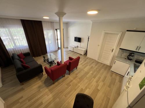 a living room with a couch and red chairs at Keyif Pension & Aparts in Cıralı