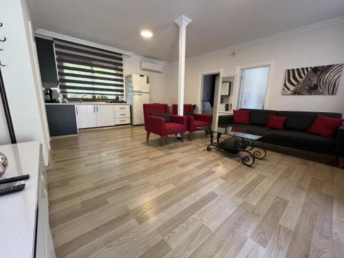 a living room with a couch and red chairs at Keyif Pension & Aparts in Cıralı