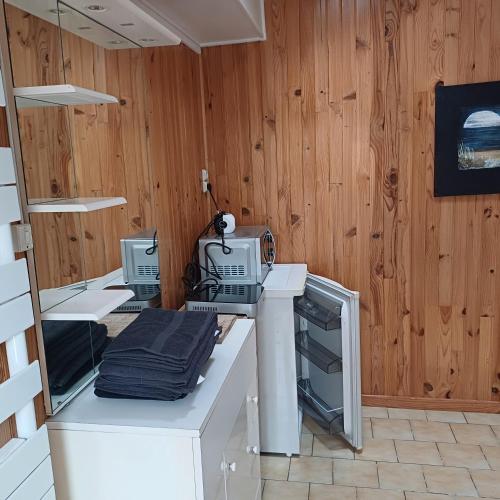 une cuisine avec des appareils électroménagers blancs sur un mur en bois dans l'établissement studio au calme sur jardin, à Saint-Sulpice-de-Royan