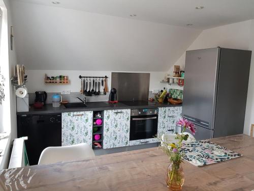 une cuisine avec un réfrigérateur en acier inoxydable et une table dans l'établissement Appartement lumineux avec terrasse proche Colmar, à Wihr-au-Val