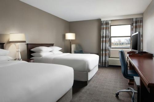 a hotel room with two beds and a desk at Sheraton Westport Lakeside Chalet in Maryland Heights
