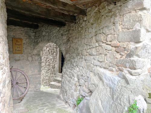 a stone building with a stone wall and a wheel at Villa Martino in Piteglio