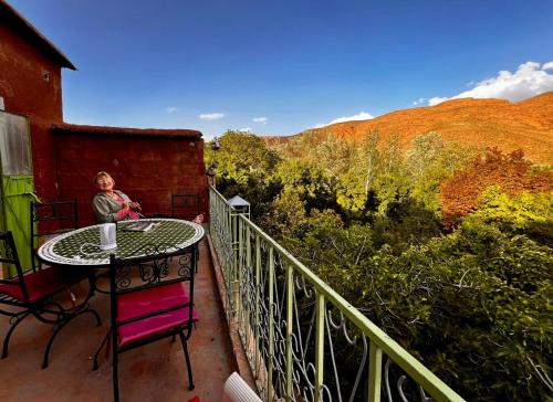 a woman sitting at a table on a balcony at DAR Moha dades in Aït Ougliff
