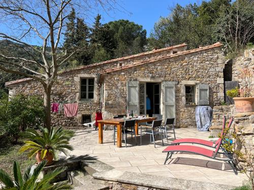 une maison en pierre avec une table et des chaises devant elle dans l'établissement Eldorado, à Chélieu