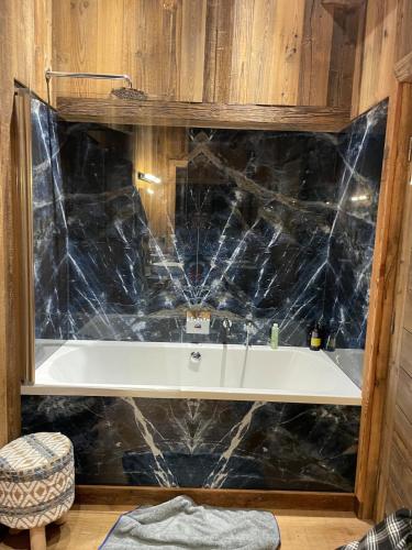 La salle de bains est pourvue d'une baignoire et d'un mur en marbre noir. dans l'établissement Le luxe sur les pistes, à Saint-Gervais-les-Bains