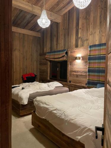 deux lits dans une chambre avec des murs en bois et des lumières dans l'établissement Le luxe sur les pistes, à Saint-Gervais-les-Bains