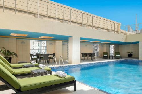 a pool in a hotel with chairs and a table at Marriott Executive Apartments City Center Doha in Doha