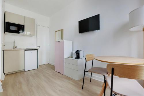 une petite cuisine blanche avec une table et une petite table et une table dans l'établissement Comfortable studio renovated at the gates of Paris, à Malakoff
