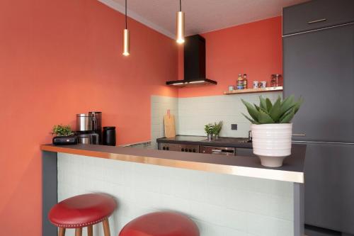 a kitchen with red walls and a counter with red stools at Strandbungalow Ostsee in Rettin