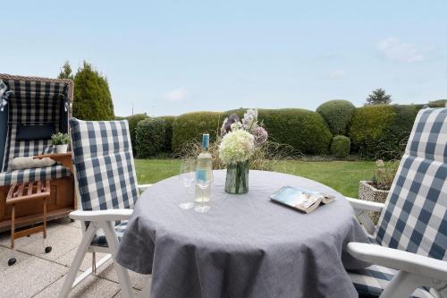a table with a vase of flowers and two chairs at Strandbungalow Ostsee in Rettin