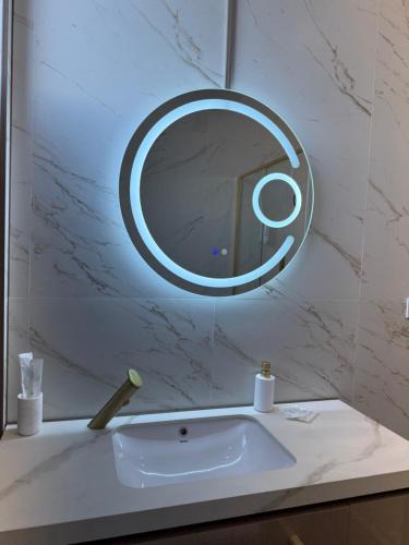 a bathroom sink with a round mirror on the wall at Galactic&Ludmila Suite SPA in Braşov