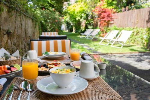 een tafel met borden en kopjes sinaasappelsap bij Rosário Suites Townhouse in Porto