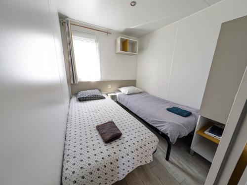 une petite chambre avec deux lits et une fenêtre dans l'établissement GHVacances Le PiPiou, à Parentis-en-Born