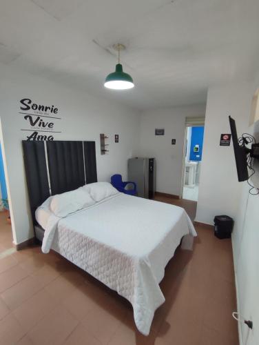 a bedroom with a white bed and a sign on the wall at OUR HOME SAN ANTONIO in Cali